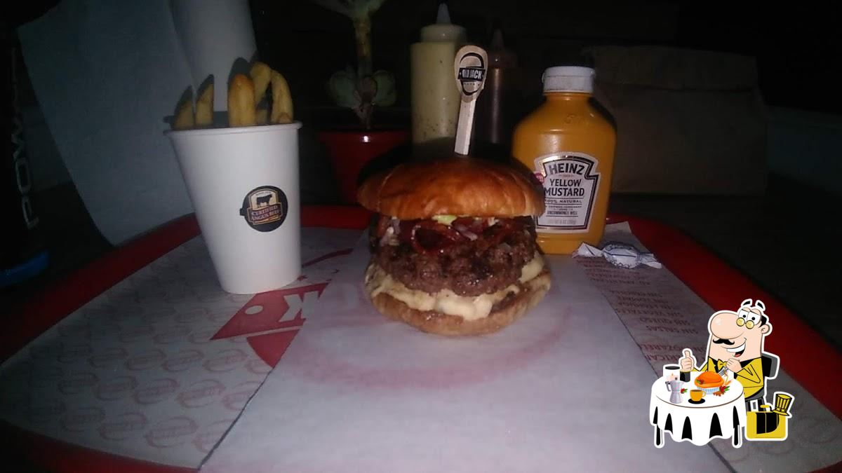 Burger Angus en empaque Old Jack con papas y mostaza en ambiente nocturno